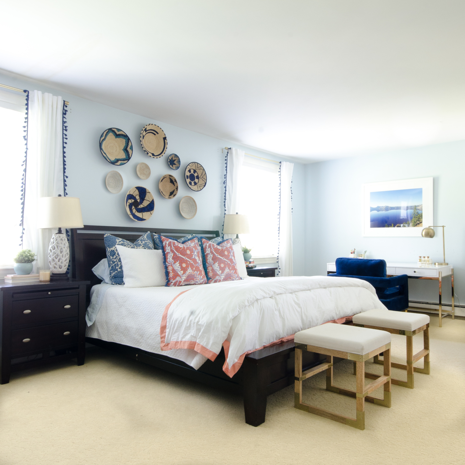 A bright, happy blue and white bedroom with pops of coral and woven basket wall art