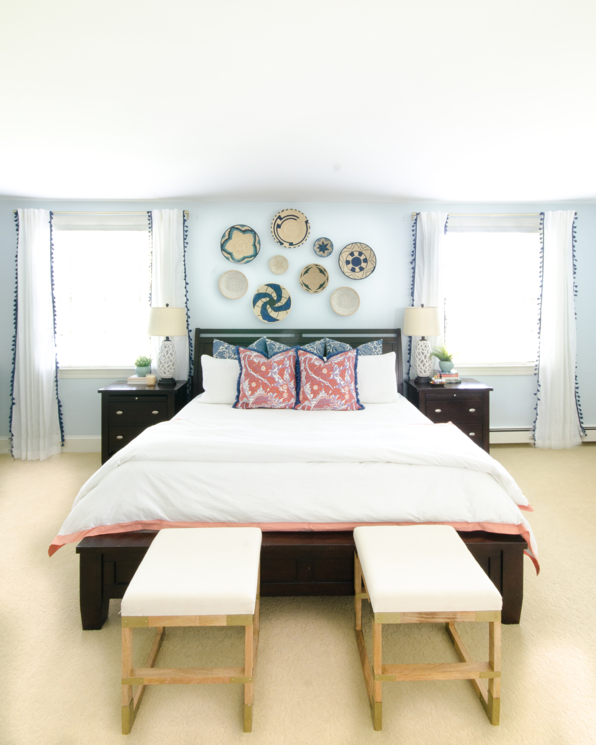 A bright, happy blue and white bedroom with pops of coral and woven basket wall art