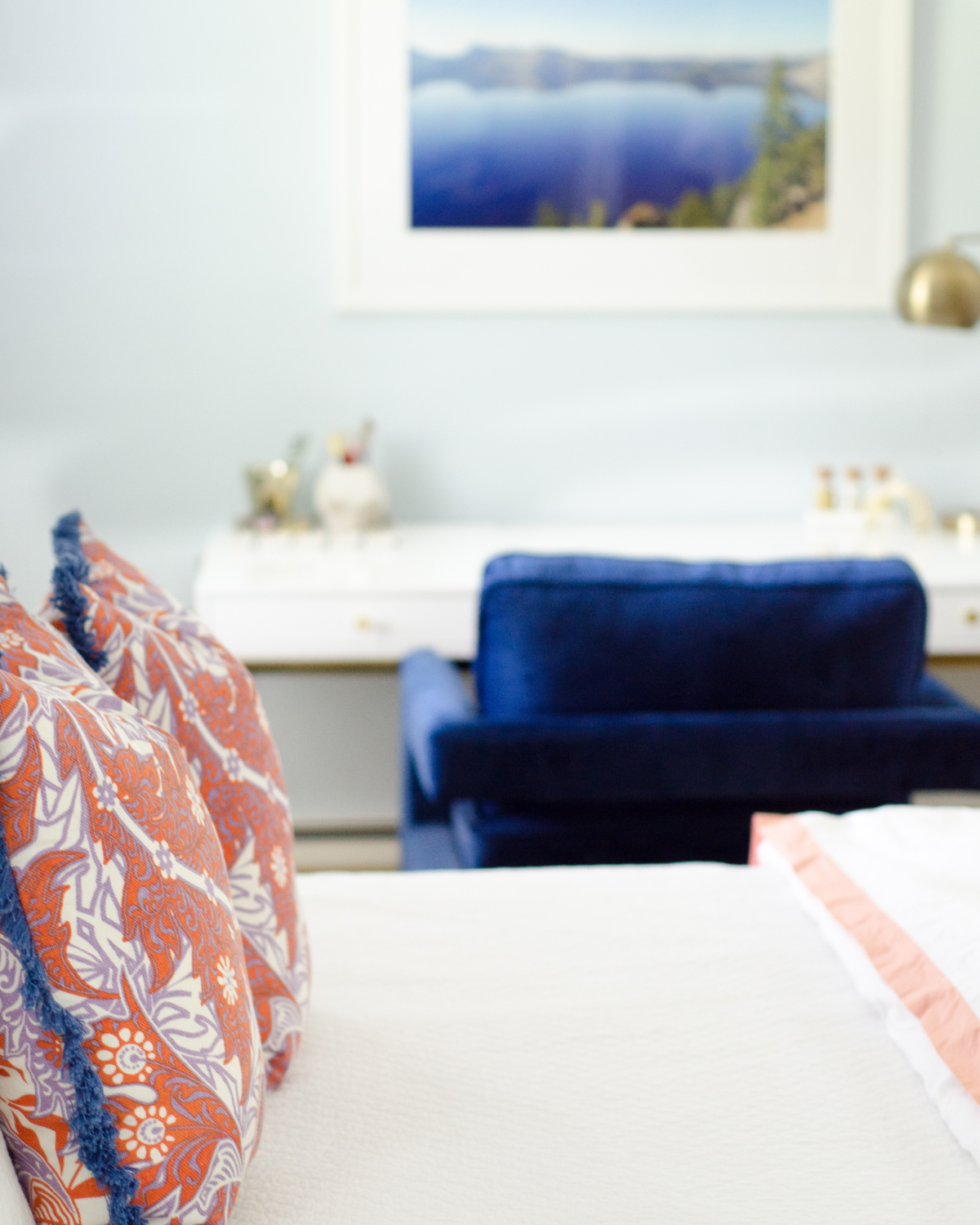 A bright, happy blue and white bedroom with pops of coral and woven basket wall art