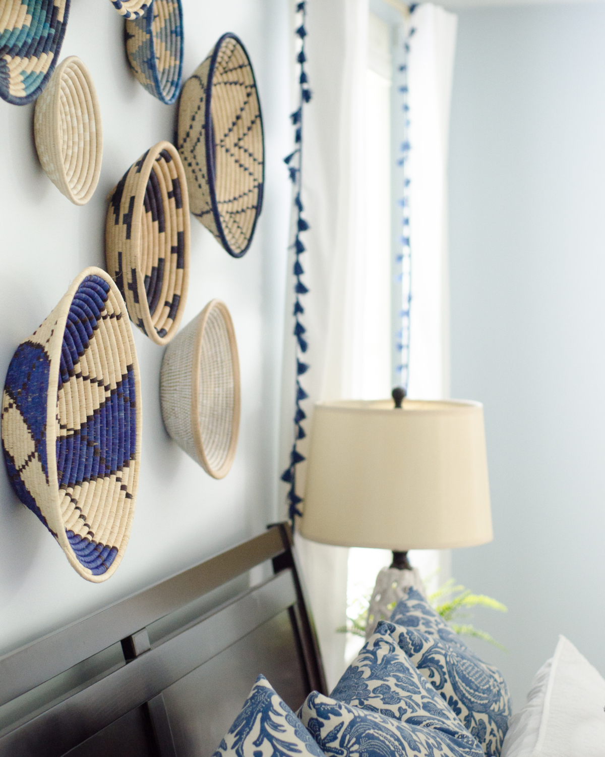 A bright, happy blue and white bedroom with pops of coral and woven basket wall art