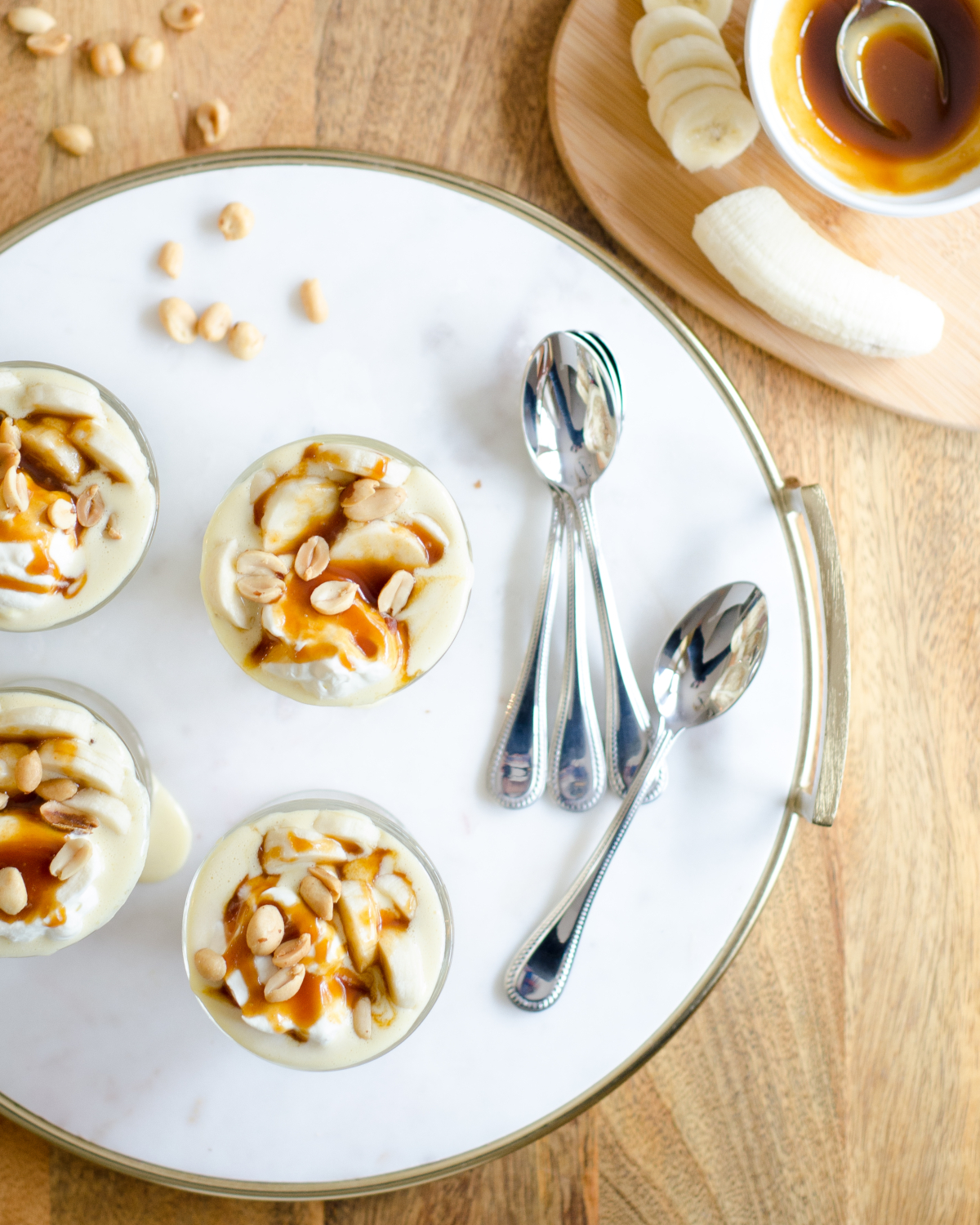 Gluten free banana cream pie recipe, in parfait form! Gorgeous individual dessert servings topped with salted caramel and peanuts for a banana cream pie like you've never tasted before!