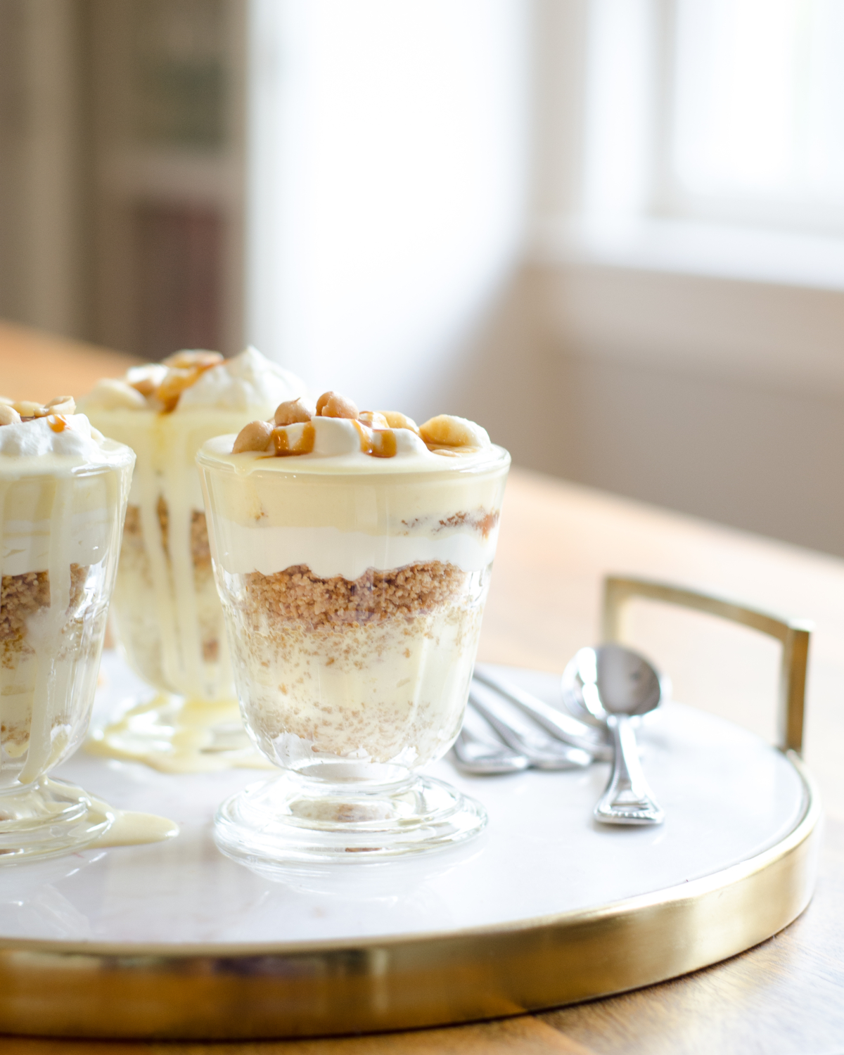 Gluten free banana cream pie recipe, in parfait form! Gorgeous individual dessert servings topped with salted caramel and peanuts for a banana cream pie like you've never tasted before!