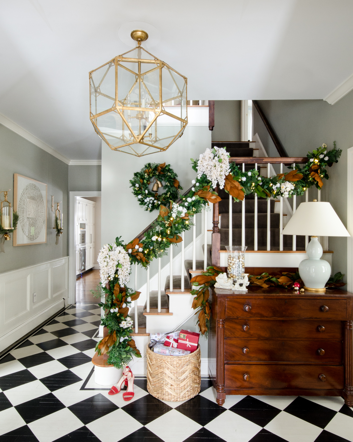 Christmas entryway with black and white checked floor, green and magnolia garland with white flowers