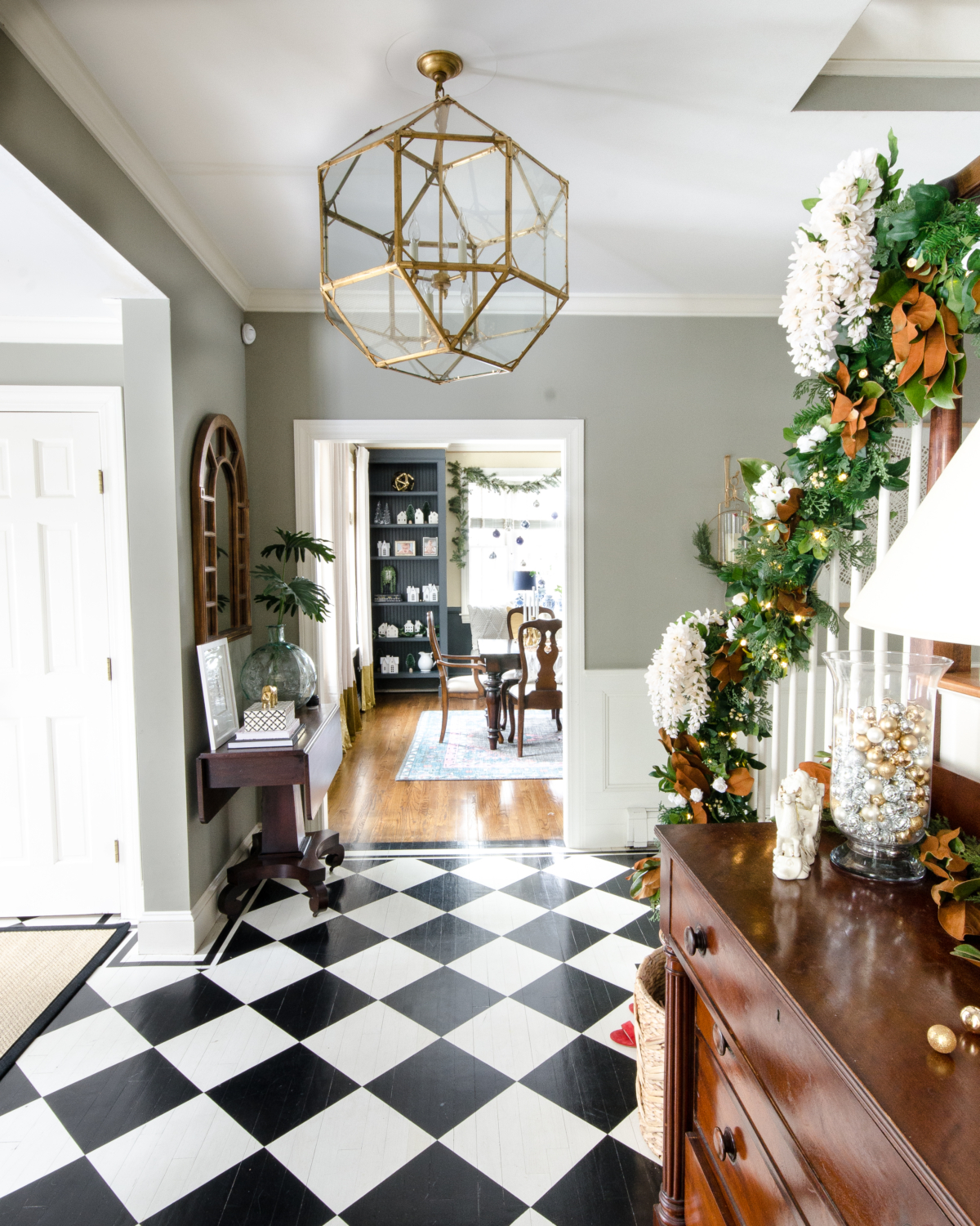 Christmas entryway with black and white checked floor, green and magnolia garland with white flowers