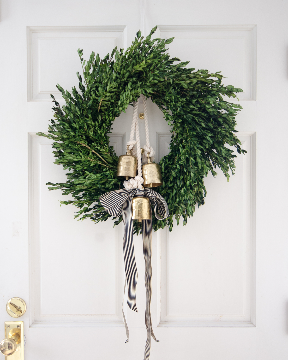 Christmas boxwood wreath, gold bells, black and white striped ribbon