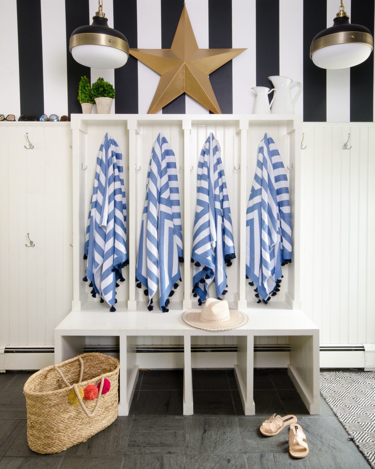 Mudroom with black and white striped wallpaper and beadboard paneling. Includes Feiss cadence pendants and features Serena and Lily Sydney beach towels. 