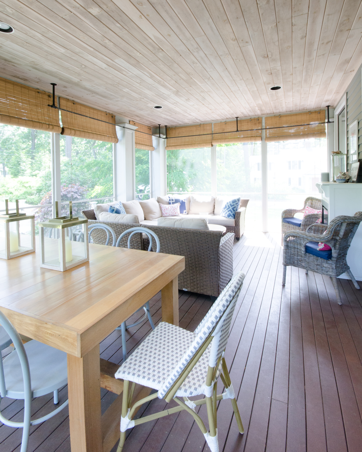 Screened porch space with dining and seating areas, a wood planked ceiling, and built in fireplace.