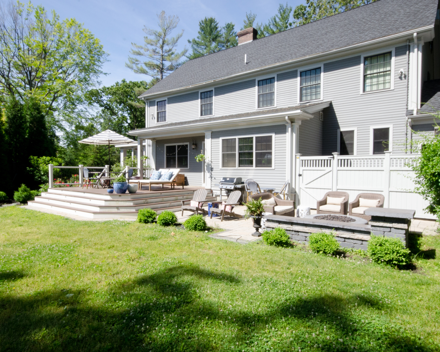 Gorgeous deck and patio spaces with lush plantings, dining space, lounge chairs, and a gas firepit.