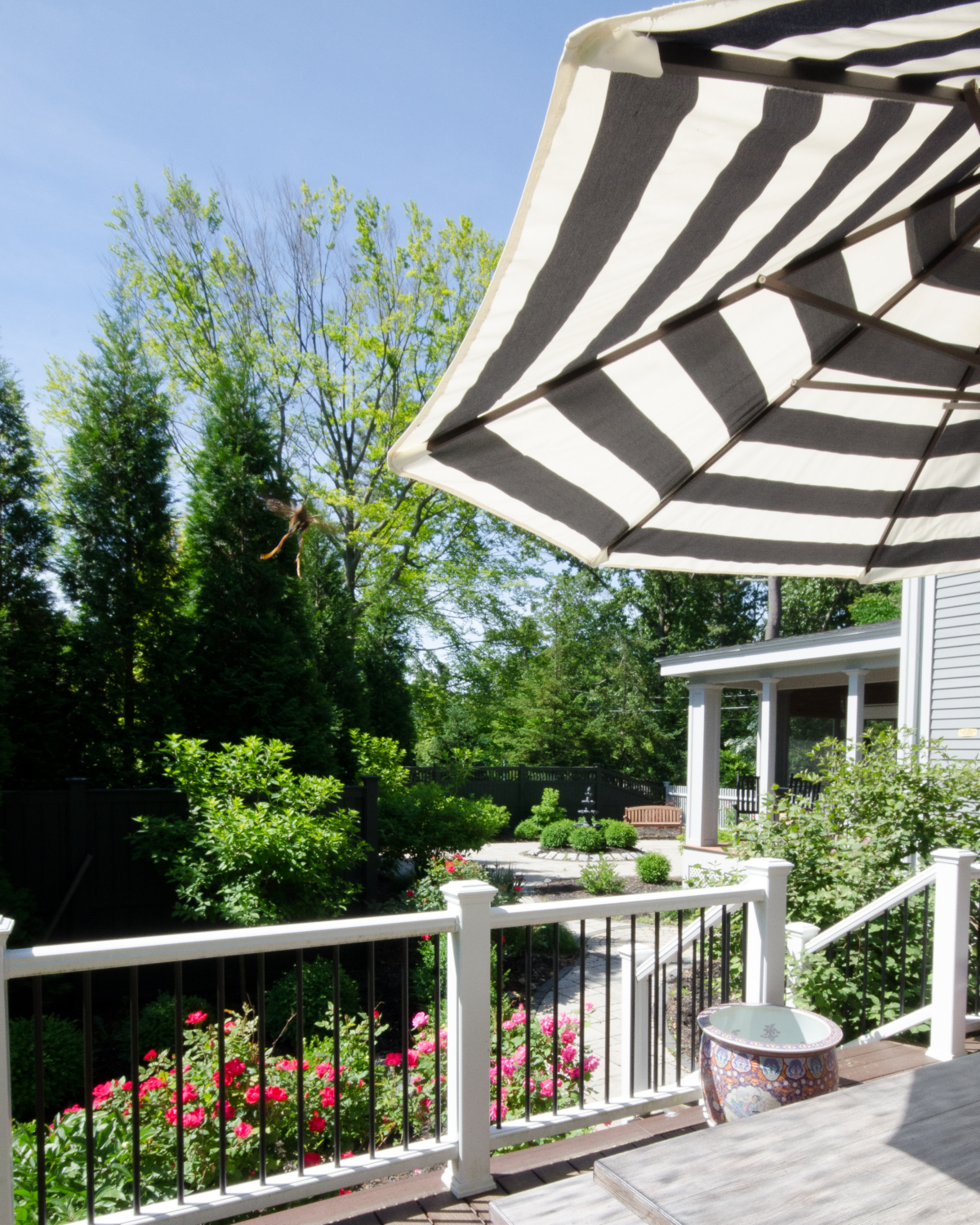 Gorgeous deck and patio spaces with lush plantings, dining space, lounge chairs, and a centerpiece fountain.