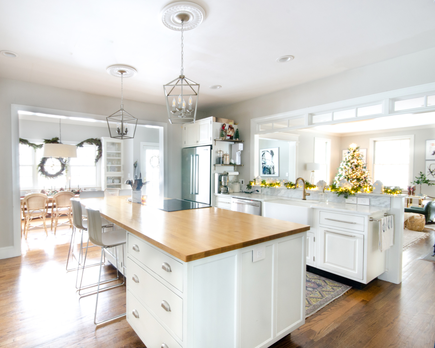 Christmas kitchen with white cabinets and butcher block counter on the island.