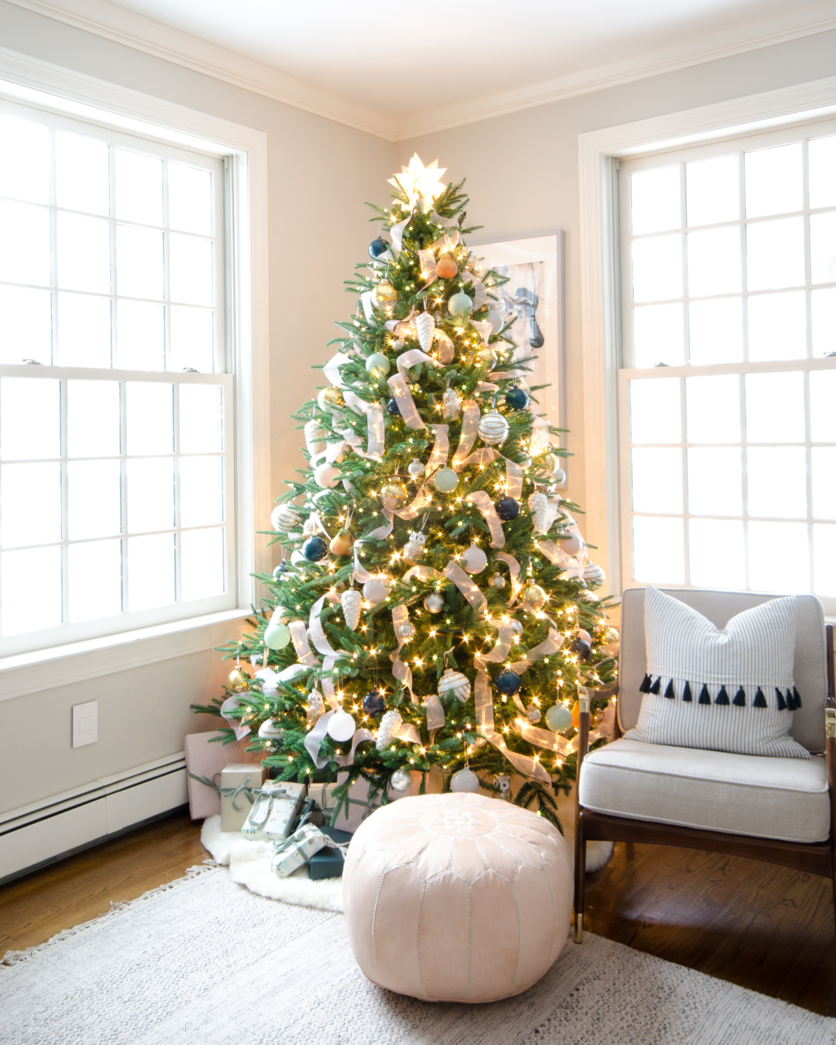 Christmas tree decorated in blush pink, deep teal, white, gold, and navy blue.