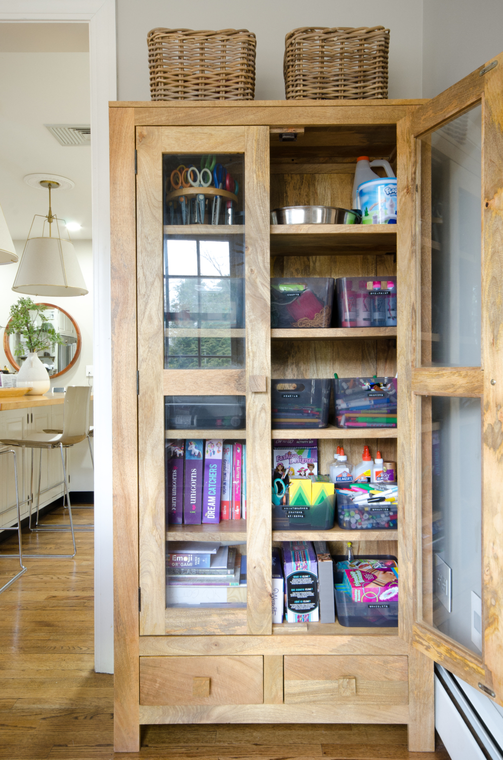 Glass front storage cabinet used to organize kids' art supplies